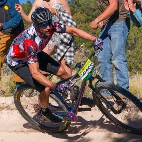 Coach riding a mountain bike on a dusty curve